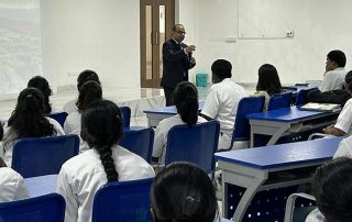 Dr. Joshi speaking to students sitting in the college hall